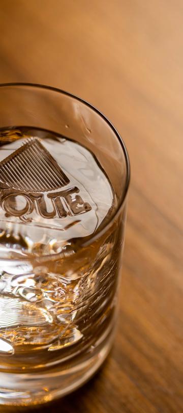cocktail glass with large ice cube branded with Pique