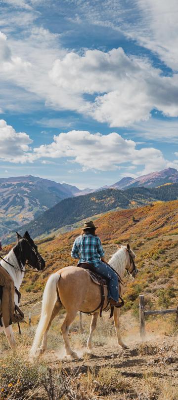 group of people on horseback ride through mountainous trails