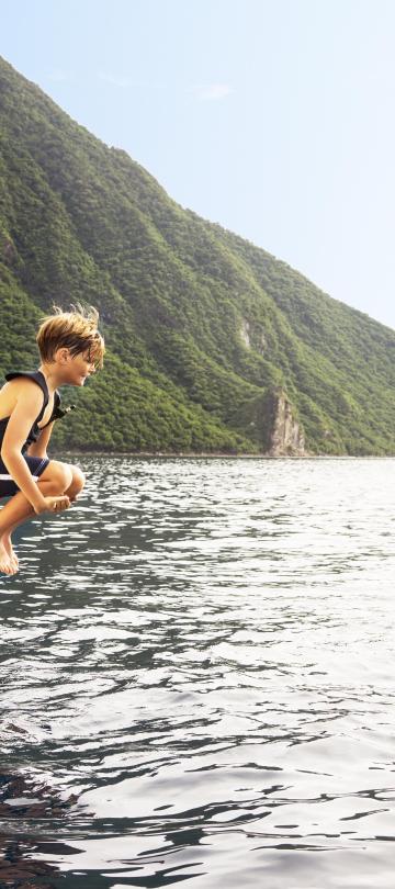 child jumps off boat toward man in water wearing snorkel