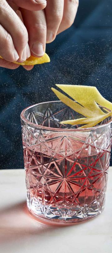 A person squeezing lemon in their cocktail