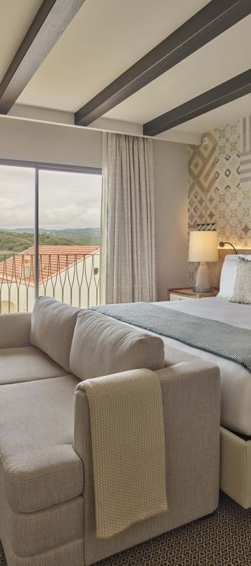 Bedroom with sofa at the foot of the bed and a small chair
