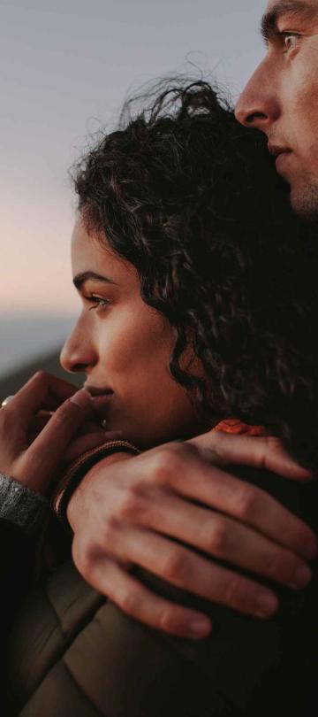 a couple hugging while watching the sunset