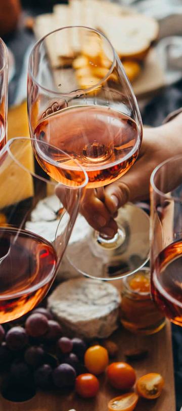Four glasses clinking in cheers over a cheese board