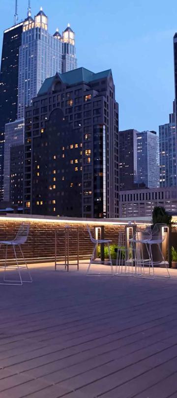 An outdoor gathering terrace at Viceroy Chicago, with high-rise Chicago architecture surrounding it at dusk