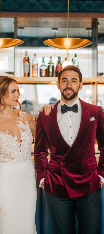 A bride and groom posing in front of a bar top