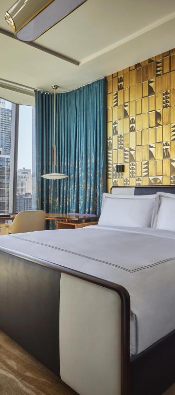 A room with floor to ceiling windows, a queen bed, and desk at Viceroy Chicago