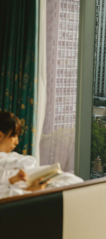 A woman laying on a bed reading a book at Viceroy Chicago