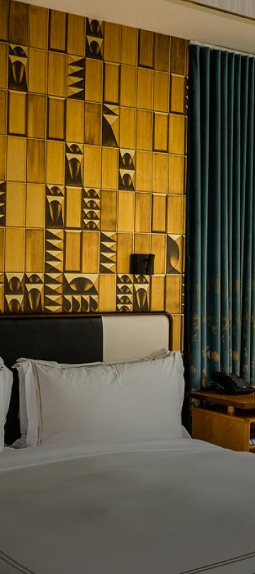 A chique hotel room with a patterned yellow accent wall at Viceroy Chicago