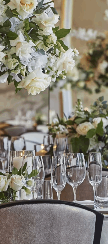 Tables setup for a wedding with floral arrangements, wine glasses, white linens, and candles at Viceroy Chicago