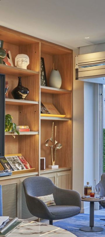 A bright meeting room adjacent to a terrace, with a large bookshelf filled with art, books and collectibles