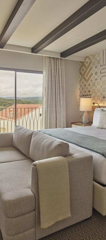 A suite with a king bed, a couch, dresser and balcony at Viceroy Ombria Algarve