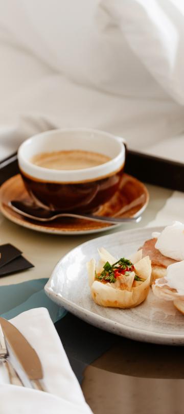 Uma bandeja de pequeno-almoço na cama, com uma sanduíche de ovo e um café