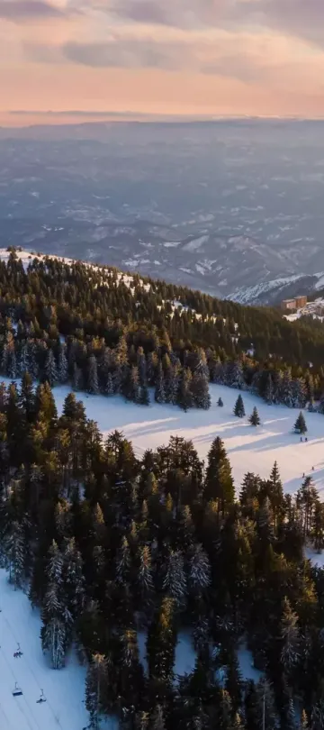 The ski slopes at Viceroy Kopaonik Serbia, with a mountain range in the background under a pink and orange sky