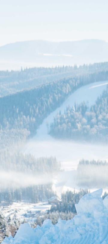 Two snowboarders on a ridge look out at the Kopaonik mountain range