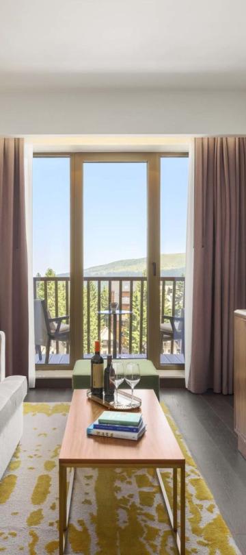 The living space with a couch, credenza, tv, and balcony in a suite at Viceroy Kopaonik Serbia