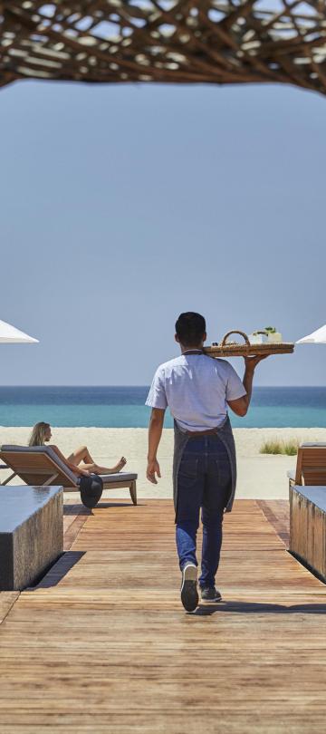A server brings drinks to the beach-side bar Nidito, a paddock adjacent to Nido restaurant