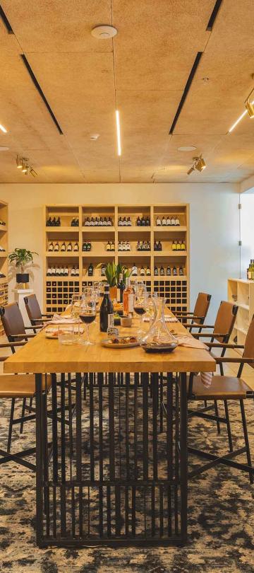 Viceroy Los Cabos' Wine Room, a bright cellar with floor-to-ceiling wine racks, surrounding a large dining table