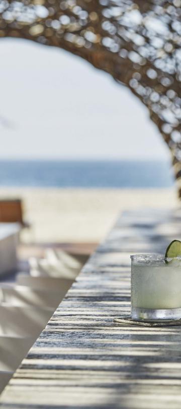 2 cocktails on a table on a patio looking onto the beach at Los Cabos