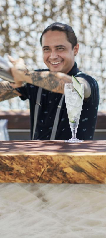 A bartender smiles while shaking a cocktail at Nido