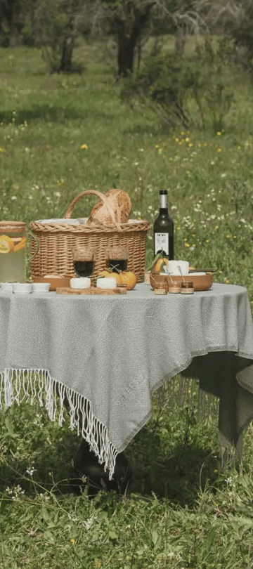 A table set up for a picnic with a basket and a bottle of wine in a field at Ombria Algarve