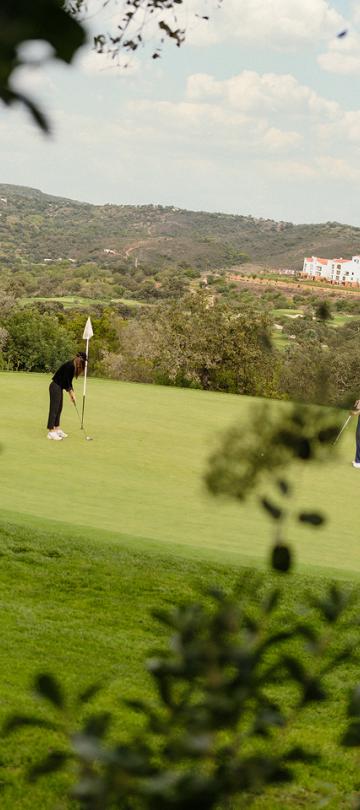 A view of two players on the green at Ombria golf course, with Viceroy Ombria Algarve in the background