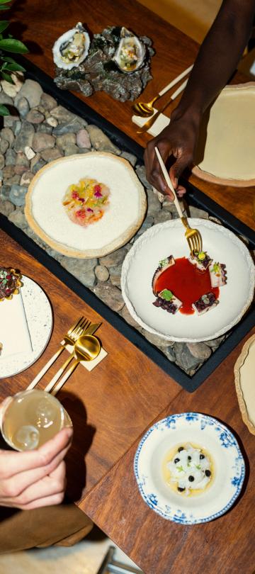 A spread of dishes to a customer at a restaurant at Ombria Algarve