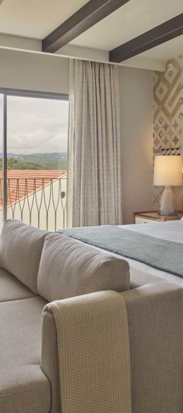 A bed with a couch and a chair in a one bedroom suite at Viceroy Ombria Algarve