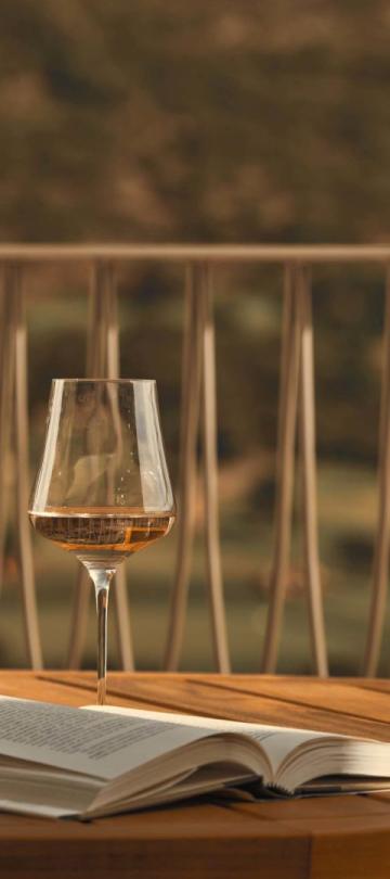 A patio table with a glass of white wine on top at Viceroy Ombria Algarve