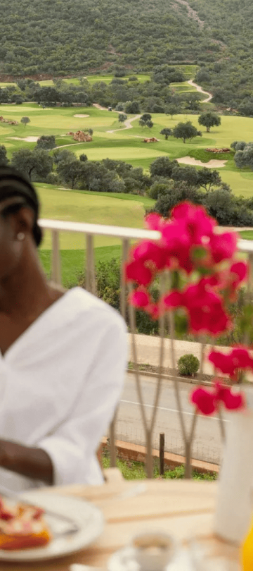 A woman reading the paper of a balcony at Ombria Algarve