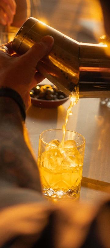 A bartender pouring a cocktail at sunset at Salpico