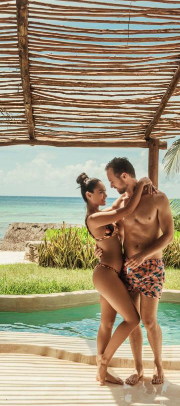 A couple in swimwear holding each other by their private pool at Viceroy Riviera Maya
