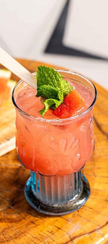 A melon-based cocktail on a table with chopped watermelon