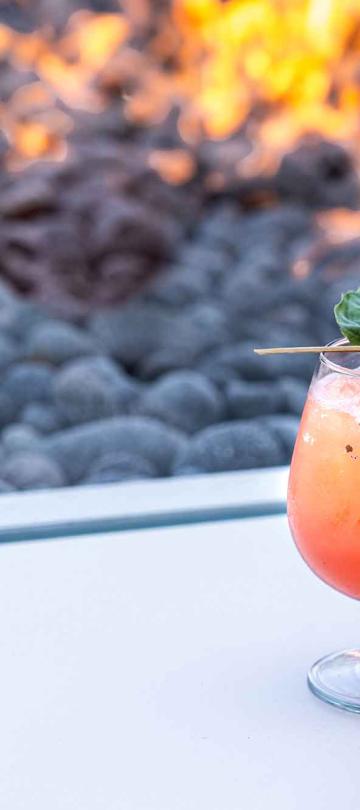 A cocktail on an outdoor table next to a burning fire