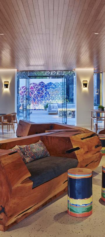 The airy hotel lobby of Viceroy Santa Monica, with large pillars and a carved log sculpture