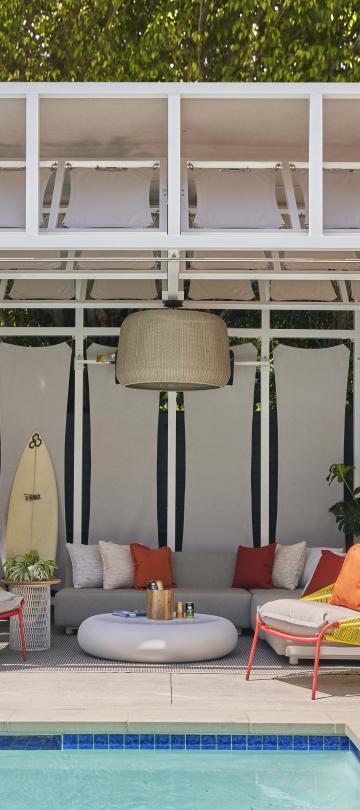 A cabana with a long couch and lounger chairs near the pool at Viceroy Santa Monica