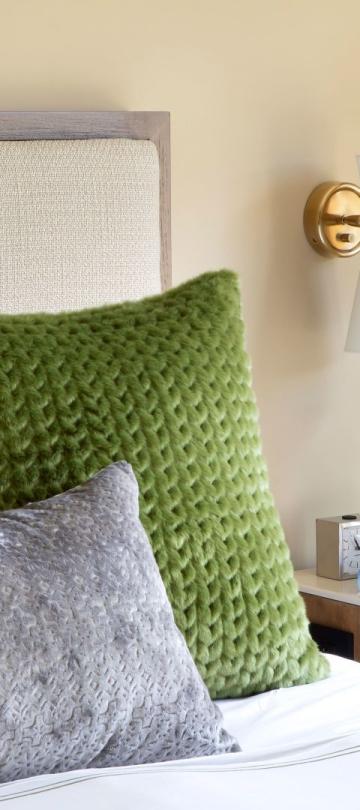 A king bed with green pillows on it and blue flowers on the nightstand in a pinnacle two bedroom residence at Viceroy Snowmass