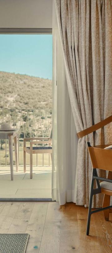 The living space with a couch, dresser , chair, and a balcony in a valley view room at Viceroy Ombria Algarve