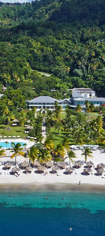 An aerial view of a beachfront resort with a mountain range behind it