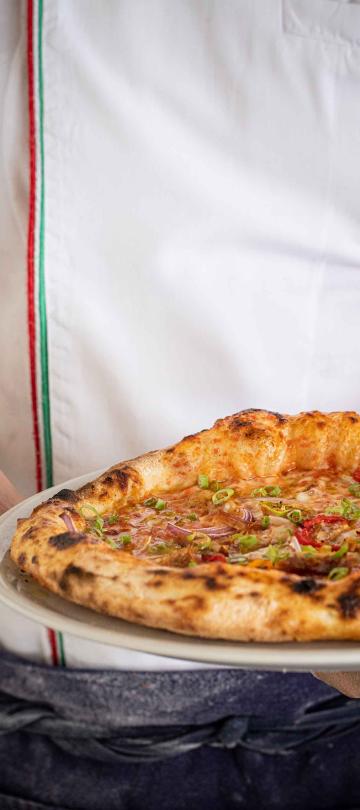 A chef holding a pizza from Bonté