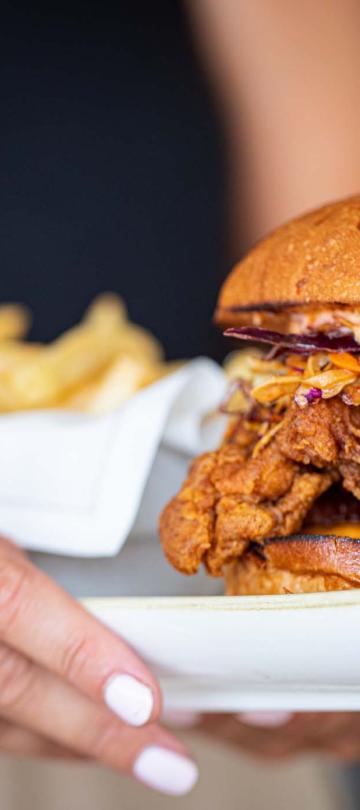 A waitress carrying a fried chicken sandwich at Bonté