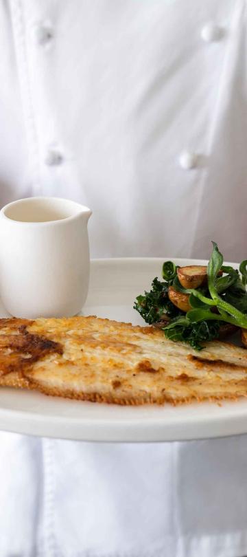 A chef holding a panfried fish dish at Saltwood Restaurant
