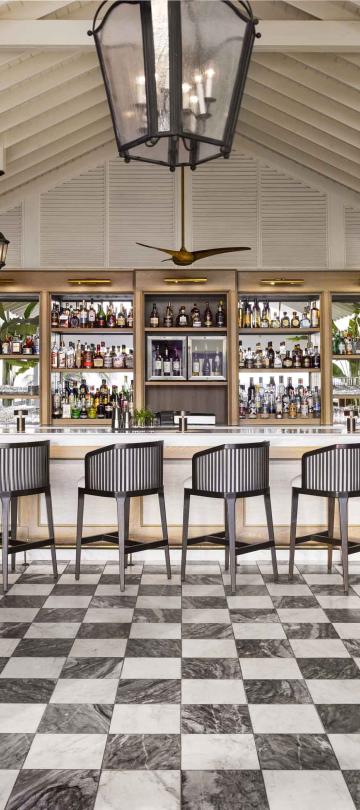 The Saltwood Bar at Sugar Beach, with a row of wood bar stools and a checkerboard floor