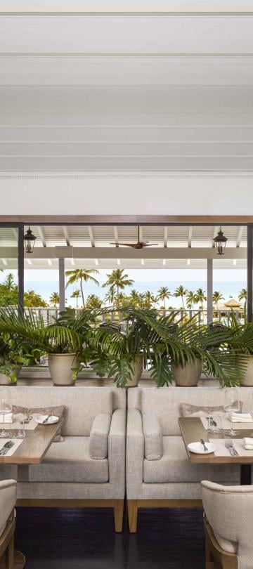 The dining room of Saltwood Restaurant at Sugar Beach, with several booths and a view of the beach outside
