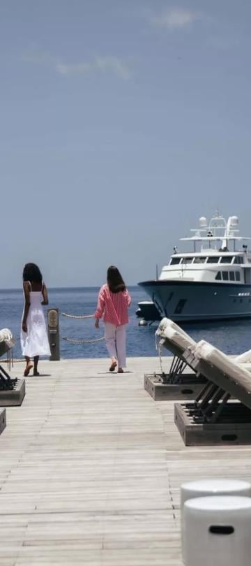 A man and woman walk on a dock at Sugar Beach as a Yacht comes to port