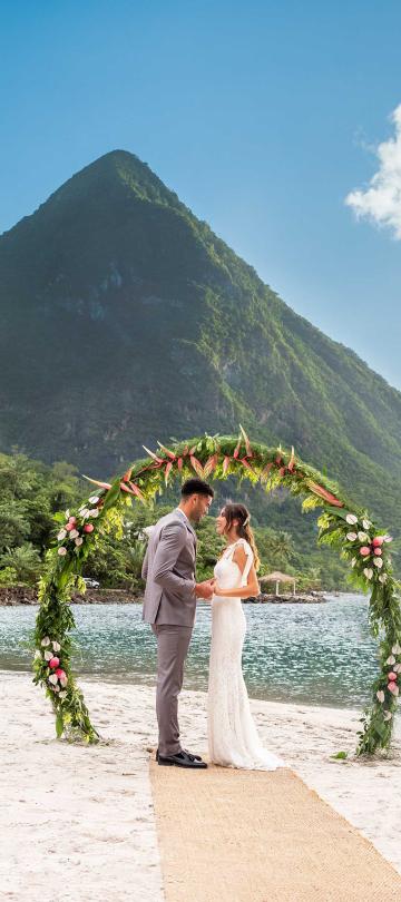 A couple getting married on the beach at Sugar Beach with themountains behind them