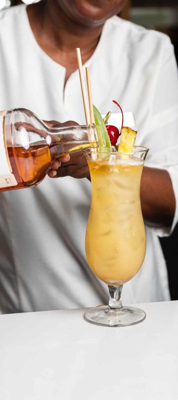 A bartender pours rum into a cocktail