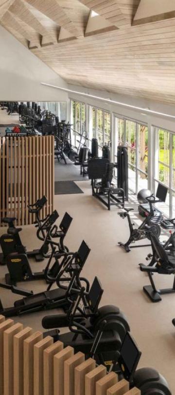 The fitness centre at Viceroy Sugar Beach, with a row of treadmills and exercise bikes looking out on a tropical landscape