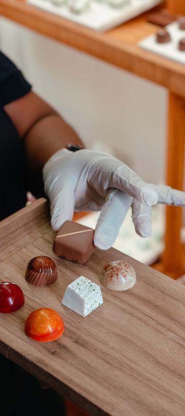 A gloved hand places high-end chocolates on a tray at Cocoa Mill