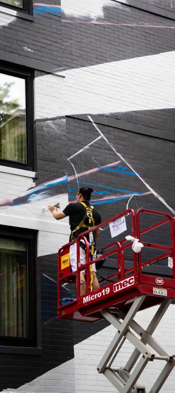 A No Kings Collective artist paints graffiti on the exterior of Viceroy Washington DC