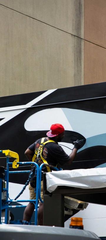A No Kings Collective artist paints graffiti on the exterior of Viceroy Washington DC